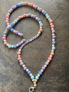 a multicolored beaded necklace with a silver charm hanging from it's end