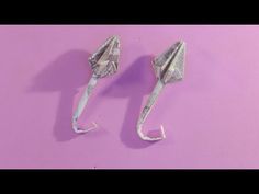 two origami umbrellas made out of money on a pink background with one folded in half