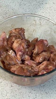 a glass bowl filled with meat sitting on top of a counter