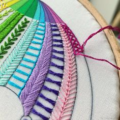 a close up of a colorful embroidery on a wooden hoop