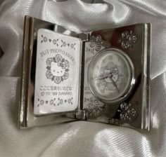 an open book with a pocket watch inside on a white cloth covered bedding area