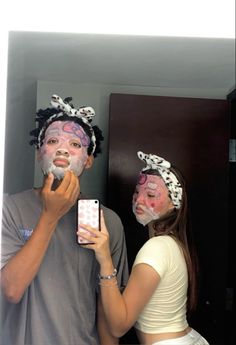 a man and woman with face paint on taking a selfie in front of a mirror