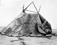 an old black and white photo of a teepee with sticks sticking out of it