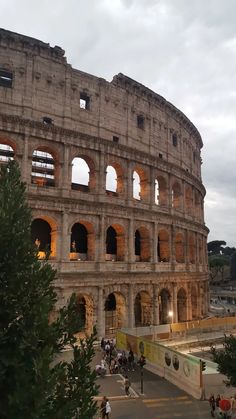 the roman colossion in rome is lit up at night with people walking around