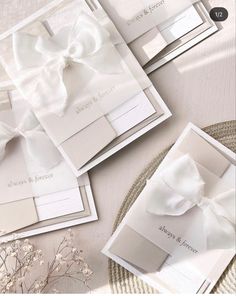 the wedding stationery is laid out on top of each other, with white bows