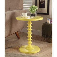 a small yellow table with a vase on it and a chair in the back ground