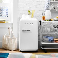 a white refrigerator freezer sitting in a kitchen next to a table with utensils