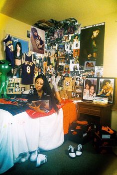 a woman sitting on top of a bed in a room filled with pictures and photos