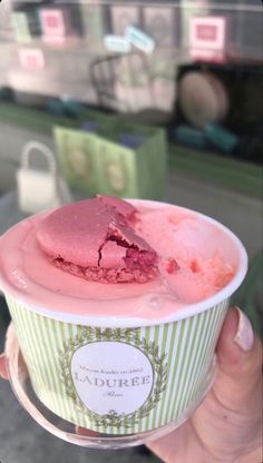 a person holding up a cup filled with ice cream and a piece of cake in it