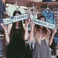 two young women holding up street signs in front of their faces with the words california and wanderlust on them