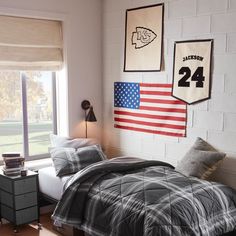 a bed room with a neatly made bed and an american flag hanging on the wall