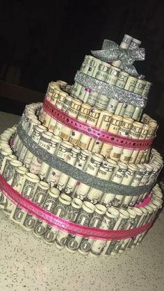 a cake made out of dollar bills with a bow on top and glitter ribbon around it