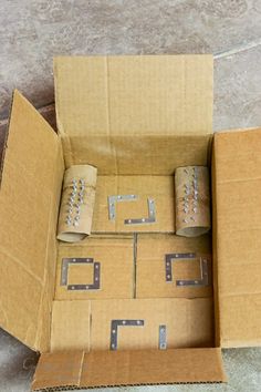 an open cardboard box with several pieces of metal in it