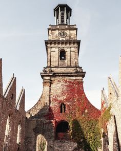 an old brick building with a clock tower in the center and ivy growing around it