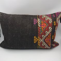 a black pillow with multicolored designs on the front and back, sitting on a white surface