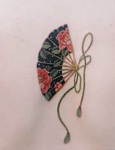 an embroidered fan with flowers on it and a string attached to the back of it