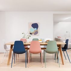 a dining room table with colorful chairs around it