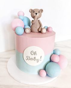 a baby shower cake with a teddy bear on top