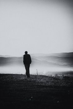 a man standing on top of a grass covered hillside