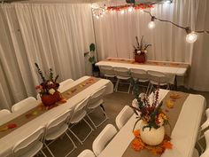 a room filled with tables covered in white tablecloths and decorated pumpkin centerpieces