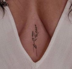 a woman's chest with a small flower tattoo on the left side of her breast