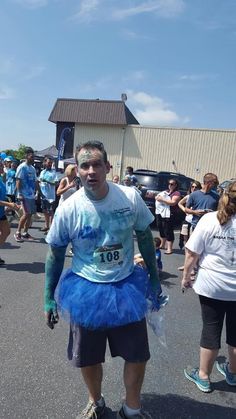 a man in blue tutu is walking down the street with other people behind him