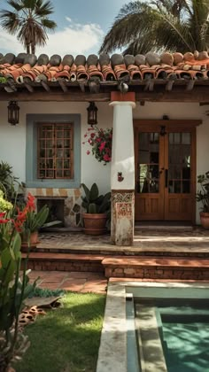 a house with a pool in front of it and palm trees around the back door