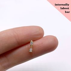 a person's hand holding a tiny diamond earring with the words interfally labret bar on it