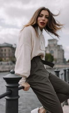 a woman standing on the edge of a bridge with her hair blowing in the wind