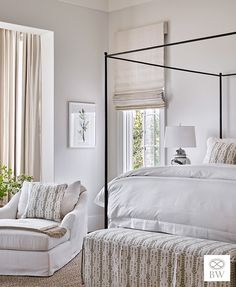 a bedroom with a four poster bed and white furniture