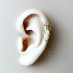 an ear with a chain around it and a turquoise stone in the middle, on a white surface