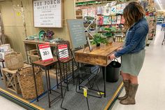 a woman standing in front of a table filled with plants