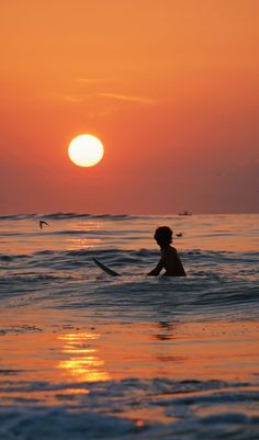 a person on a surfboard in the ocean at sunset