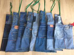 five pairs of jeans are lined up in a row on the floor, with green string attached to them