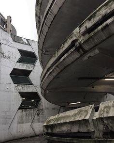 an abandoned building with concrete stairs and balconies on the outside, next to a parking garage