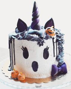 a white cake with black icing and decorations on it's top, sitting on a plate