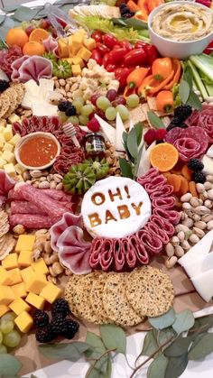 a platter filled with meats, cheeses and fruit for a baby shower