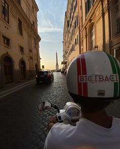 a man riding a motorcycle down a street next to tall buildings