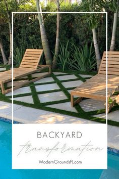 two wooden lounge chairs sitting next to a swimming pool with grass on the ground and palm trees