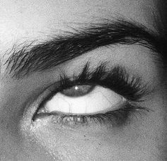 the eye of a woman with long lashes and eyelashes on her face, black and white photograph