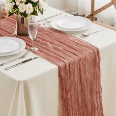 the table is set with white and pink flowers in a vase on top of it