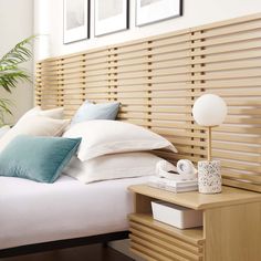 a bed with white sheets and pillows in a bedroom next to a wooden slatted headboard