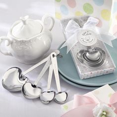 a tea set with spoons and measuring spoons on a plate next to a gift box