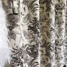 the curtains are covered with black and white prints on them, along with plants and trees