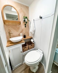 a white toilet sitting in a bathroom next to a wooden counter top under a mirror