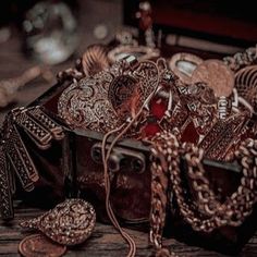 a box filled with lots of jewelry on top of a wooden table next to other items