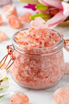 a glass jar filled with lots of pink sea salt sitting on top of a table