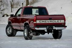 a red pick up truck parked in the snow