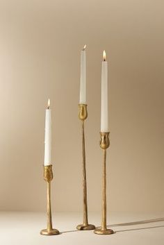 three candles are standing next to each other with one candle in between them and the other on its side