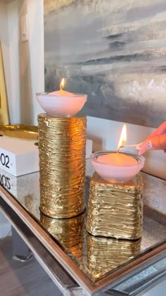 two gold candles sitting on top of a glass table